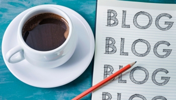 コーヒーとノートパッドと鉛筆が写った写真。ノートパッドには、ブログと書かれている。